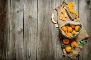 Fragrant tangerines in an old bag with a knife and peeled tangerines. photo