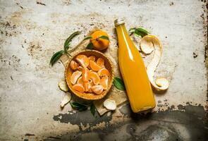 Peeled tangerines with leaves and juice in the bottle. photo