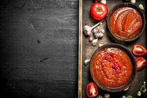 Fresh tomato sauce with spices and garlic on wooden tray. photo