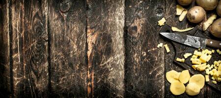 The sliced potatoes on an old wooden Board. On wooden background. photo