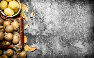 Fresh potatoes in an old tray. On rustic background photo