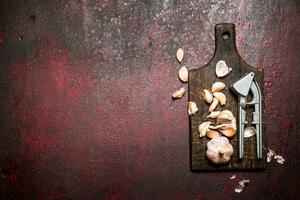 Fragrant garlic with a press tool on a wooden Board. On rustic background. photo