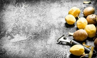 Peeled organic potatoes. On rustic background. photo