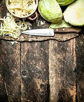 Shredded fresh cabbage on the Board. On the old wooden table. photo