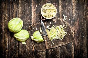 Shredded fresh cabbage on the Board. On the old wooden table. photo