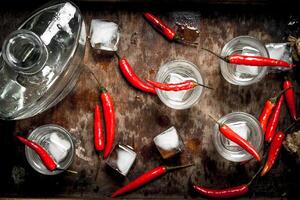 Vodka shots with chili peppers on a wooden tray. photo