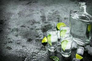 Vodka with pieces of lime and ice cubes. photo