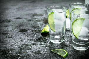 Vodka with pieces of lime and ice cubes. photo