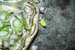 Vodka with lime and ice on a steel tray. photo