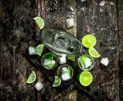 Vodka shots with lime and ice on the board. photo