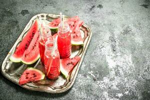 Watermelon juice in bottles on a steel tray. photo