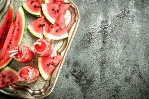 Watermelon juice in bottles on a steel tray. photo