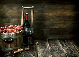 rojo vino con un Cubeta de uvas. foto