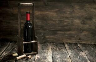 Wine background. A bottle of red wine on a stand with a corkscrew. photo