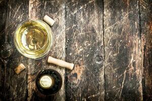 glass of white wine with a corkscrew. photo