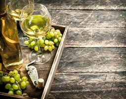 White wine with fresh grapes on an old tray. photo