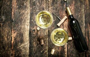 glass of white wine with a corkscrew. photo