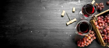 Wine background. Red wine in an old box with a corkscrew. photo