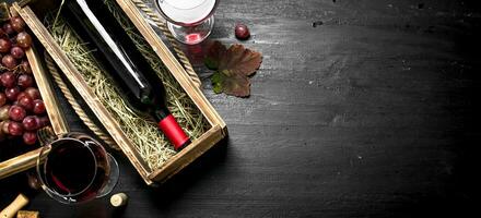 Wine background. Red wine in an old box with a corkscrew. photo