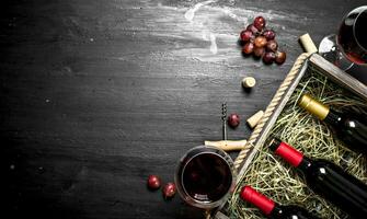 Wine background. Red wine in an old box with a corkscrew. photo