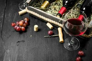 Wine background. Red wine in an old box with a corkscrew. photo