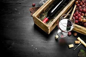 Wine background. Red wine in an old box with a corkscrew. photo