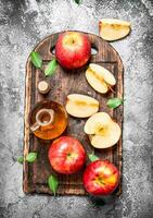 Apple cider vinegar with fresh apples on cutting Board. photo