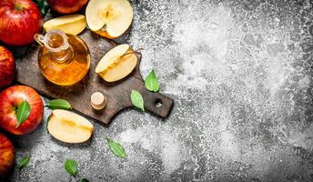 Apple cider vinegar with fresh apples on cutting Board. photo