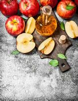 Apple cider vinegar with fresh apples on cutting Board. photo