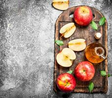 Apple cider vinegar with fresh apples on cutting Board. photo