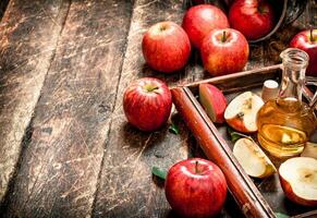 Apple cider vinegar, red apples in the old tray . photo