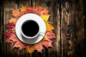 Cup of hot coffee with autumn leaves. photo