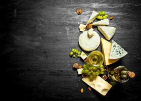 glass of white wine with different cheeses , grapes and nuts. photo