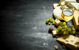 glass of white wine with different cheeses , grapes and nuts. photo