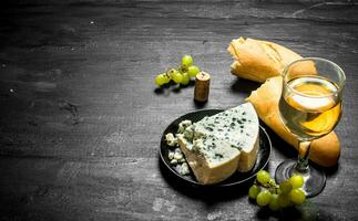 glass of white wine with blue cheese and ciabatta . photo