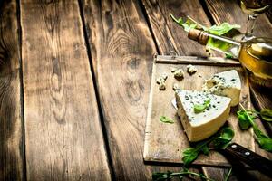 Bottle with white wine and blue cheese on cutting Board. photo