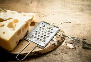 piece of cheese and the grater on the Board. photo