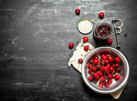 Cherry jam and metal tool for cherries. photo