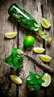 The ingredients for the cocktail - limes, mint, knife, is also prepared cocktail in the bottle and in the glass. photo