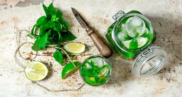 Ingredients for making mojitos - lime, mint leaves, rum, citrus knife and an old table. photo