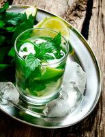 Fresh cocktail of lime, mint, rum and ice on a metal tray . On a wooden table. photo