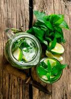 Cooked cocktail of lime, mint, rum and ice on wooden table . Top view photo