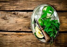 Fresh cocktail of lime, mint, rum and ice on a metal tray . On a wooden table. Free space for text . photo