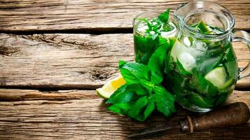 Cooked cocktail of lime, mint, rum and ice on wooden table . Top view photo