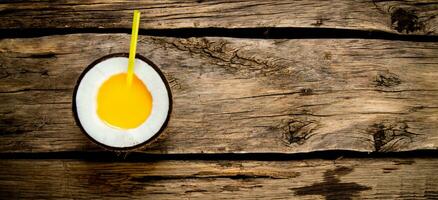 Fresh cocktail in coconut cup on wooden background. photo