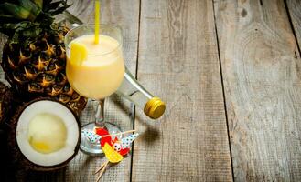 Fresh cocktail in the glass, rum, coconut and pineapple on a wooden table. Free space for text. photo