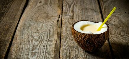 Fresh cocktail in coconut cup on wooden background. Free space for text. photo