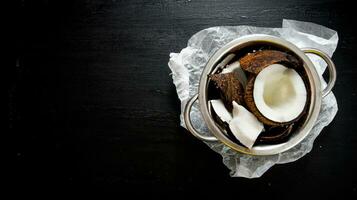 Coconut in metal bowl on the chalkboard . Free space for text. photo