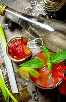 The cocktail bloody mary . Making a cocktail with vodka, tomato paste and other ingredients on wooden background . photo