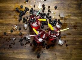 Making cocktail of berries , ice and lemon on wooden background. photo